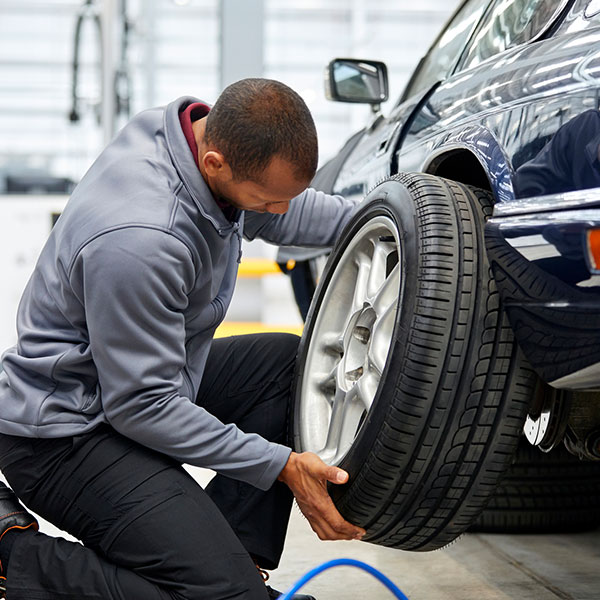 Full length of young engineer adjusting car tire
